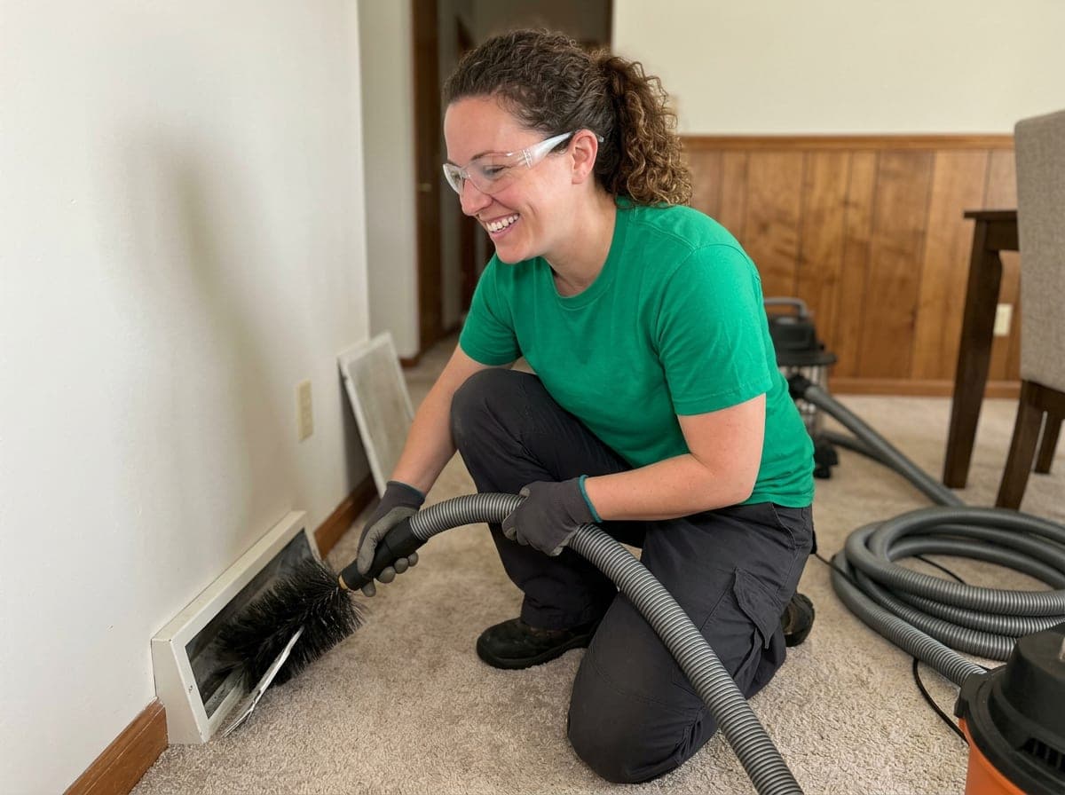 Technician running a vacuum hose through a home's duct system