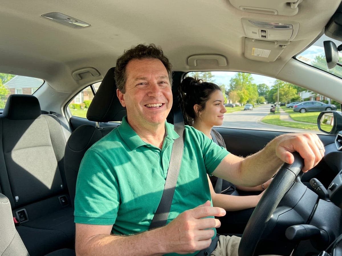 A driving instructor coaches a student turning a dual-control car down a quiet test route street.
